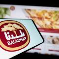 Stuttgart, Germany, 11-03-2023: Person holding cellphone with logo of Qatari dairy and food company Baladna in front of business website. Focus on