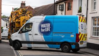 Southern Water company van and other vehicles parked blocking road while fixing a burst water main, Overton, Hampshire, England, UK