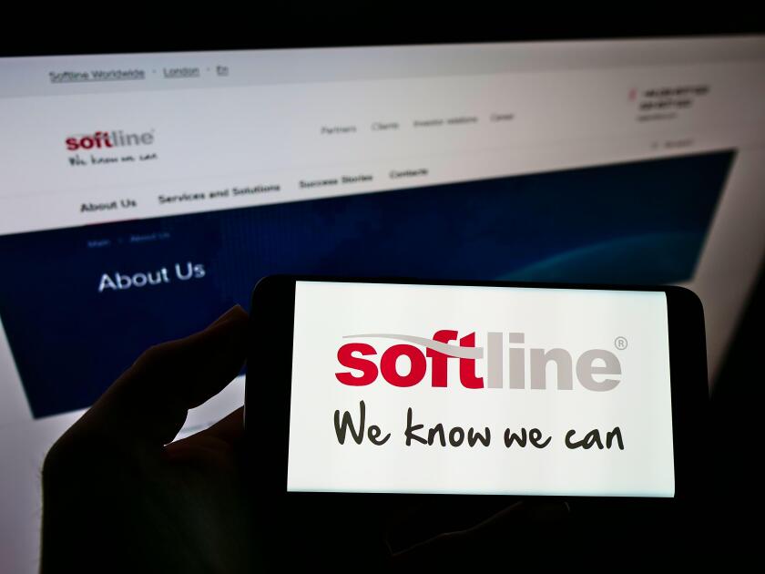 Person holding cellphone with logo of global IT solutions provider Softline International on screen in front of webpage. Focus on phone display.
