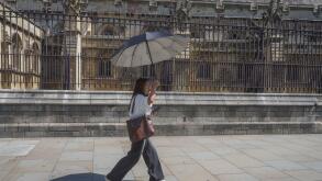 UK Heatwave: 22 June 2026  A pedestrian in Westminster shelters with an umbrella on hot sweltering day in London