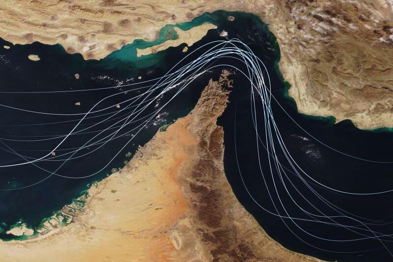 Satellite view of the Strait of Hormuz with white graphic lines representing global shipping lanes and maritime traffic between the Persian Gulf and G