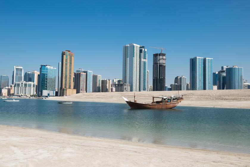Traditional boat with modern skyline, Emirate of Sharjah, UAE.