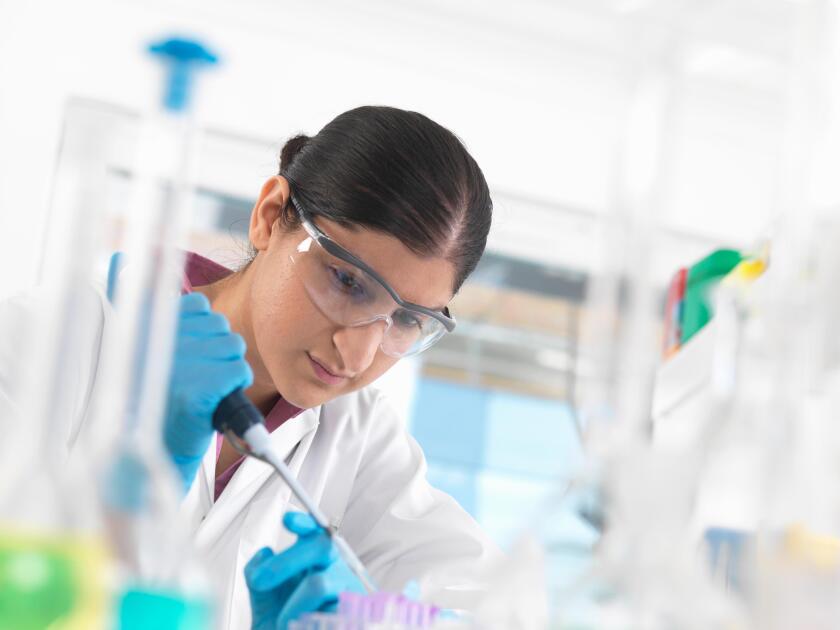 Young woman scientist  pipetting sample into vial in a laboratory used for chemical and DNA testing