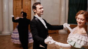 Portrait of smiling gentleman wearing classic tailcoat dancing with young lady during debutante ball in palace, copy space
