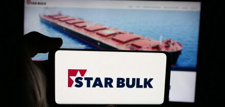 Stuttgart, Germany - 12-16-2025: Person holding cellphone with logo of shipping company Star Bulk Carriers Corp. on screen in front of webpage.