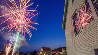 July 4th fireworks explode over a harbor on the Maine coast in celebration of Independence Day.