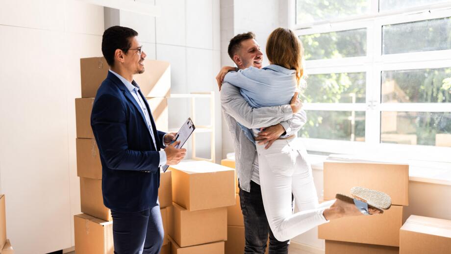 Real Estate Agent And Happy Couple Moving Into New Home