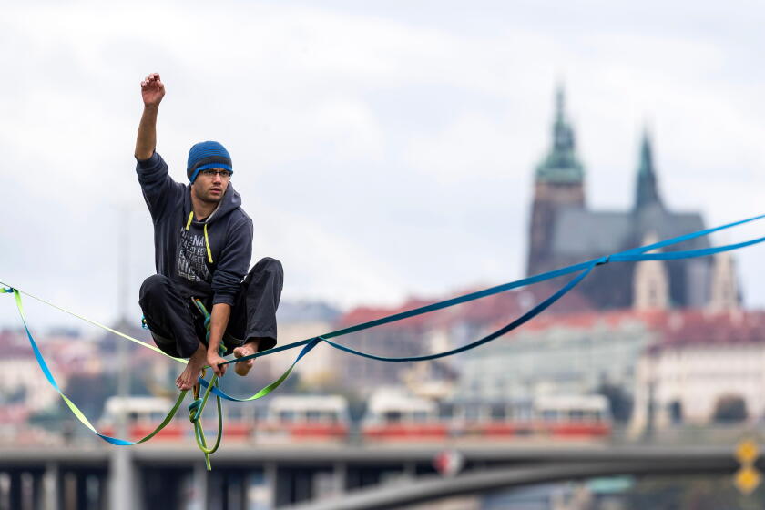 a tightrope walker on slack line above the Vltava river with background of panorama of Prague Castle, Czech republic