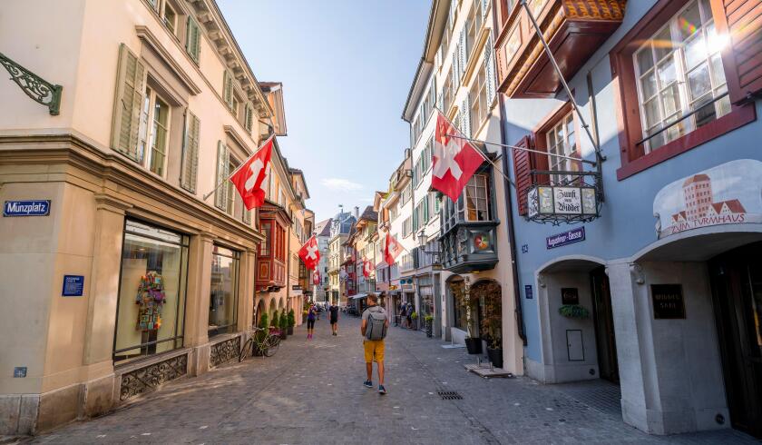 Tourist in Augustinergasse, alleyway with historic houses and Swiss flags in the old town, Zurich, Switzerland