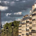 Dark clouds surround  The Eiffel Tower as seen  from Rue Soufflot , a street lined with impressive apartment buildings ,Paris ,France