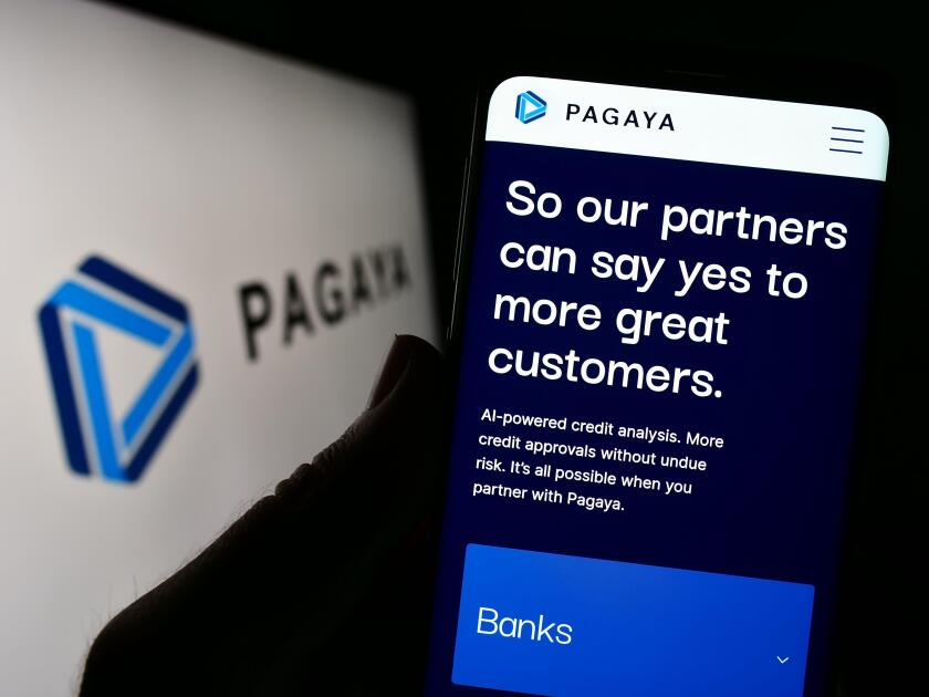 Person holding cellphone with webpage of financial company Pagaya Technologies Ltd. on screen in front of logo. Focus on center of phone display.