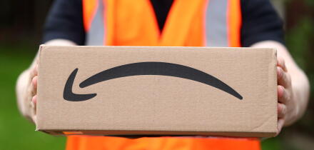 A man delivering an Amazon box with the Amazon smile logo in the UK