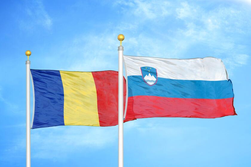 Romania and Slovenia two flags on flagpoles and blue sky