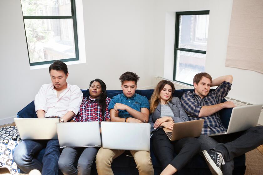 Tired business people using laptop while reclining on sofa in office