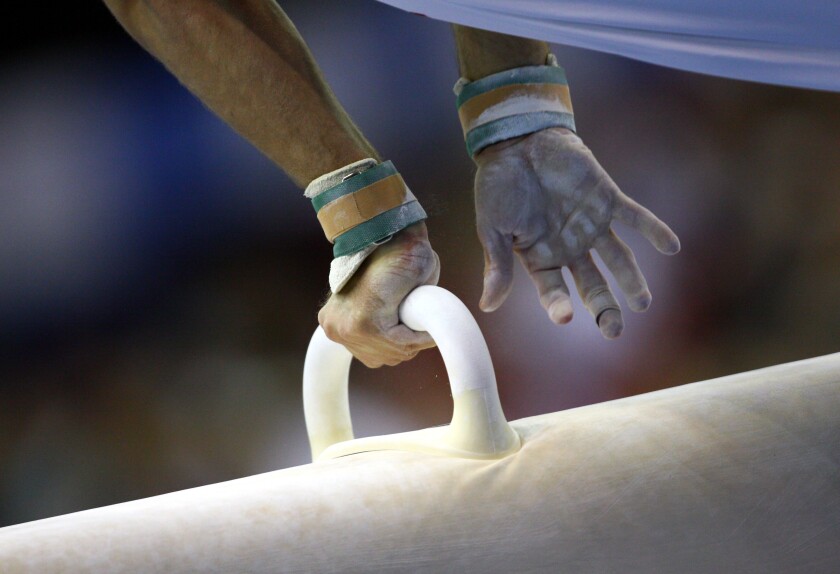 male gymnast competes on pommel horse at a gymnastics competition