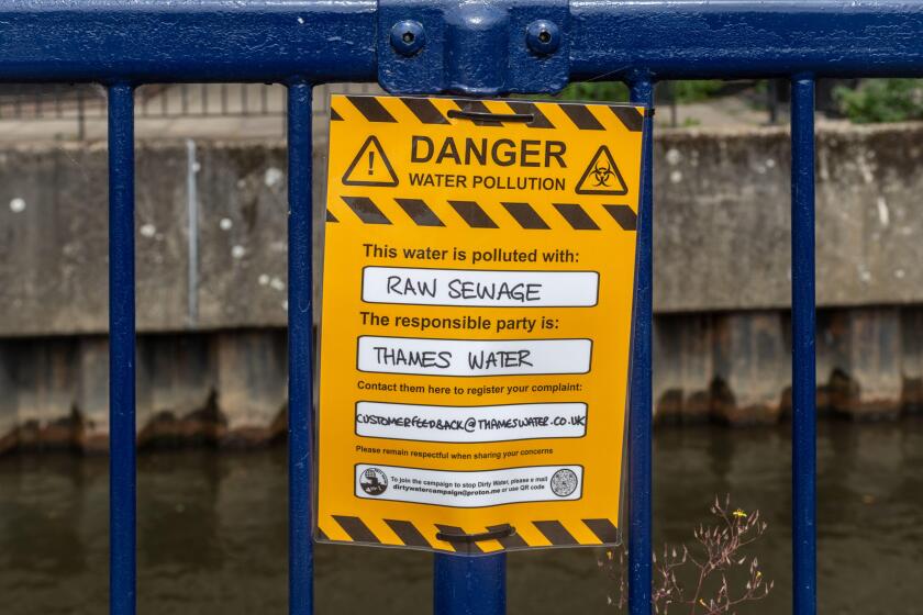 Protest sign reading Danger water pollution, this water is polluted with raw sewage. The responsible party is Thames Water. River Wey, Guildford, UK