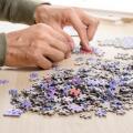 The man playing jigsaw puzzle game (focus at heap of jigsaw)