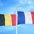 Belgium and France two flags on flagpoles and blue cloudy sky