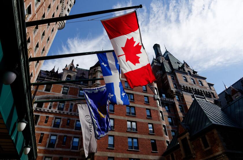 Quebec Flag (Fleur de Lys) and the Canadian flag (Maple Leaf) flying outside the Chateau Frontenac Hotel in Quebec City, Canada