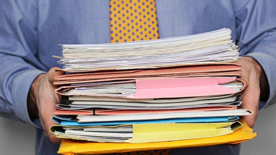 Overworked Businessman Carrying a Stack of Paperwork. Close Up.