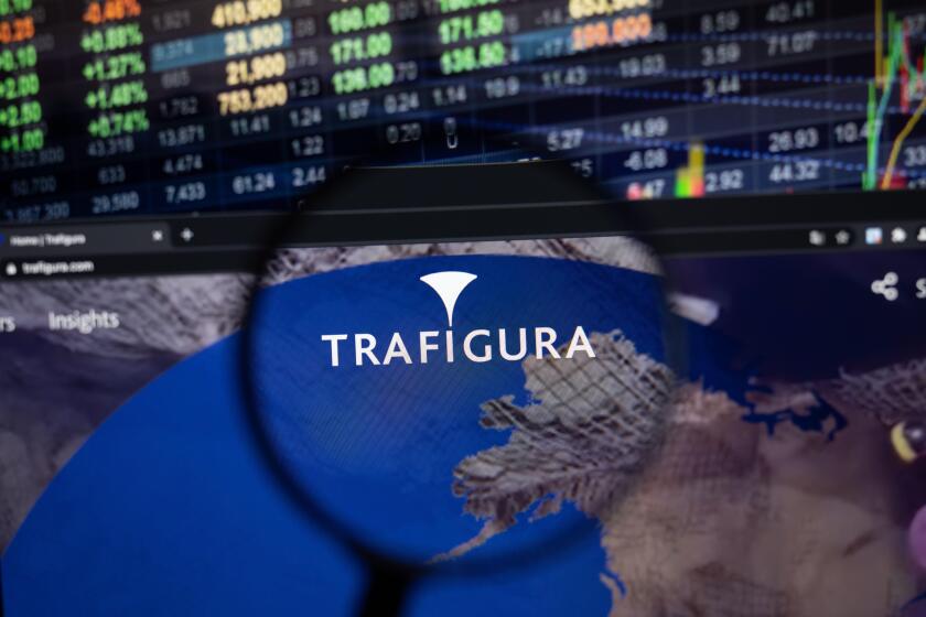 Trafigura company logo on a website with blurry stock market developments in the background, seen on a computer screen through a magnifying glass