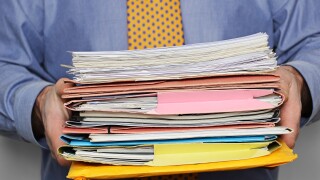 Overworked Businessman Carrying a Stack of Paperwork. Close Up.