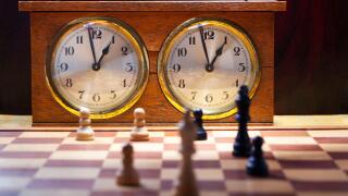 Old wooden vintage chess clock with an endgame on chessboard