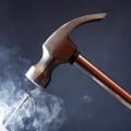 Work tool. Metal hammer above nail with smoke on nice dark background