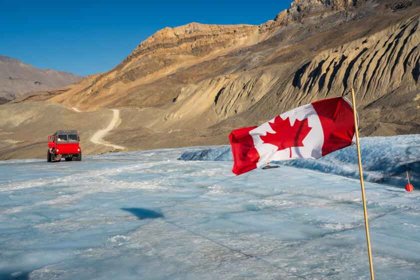 Canadian flag and Ice explorer vehicle on Athabasca glacier of Columbia Icefield, Jasper National Park, Alberta, Canada.