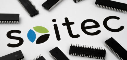 SOITEC company logo on the paper document and large microchips placed around. Illustrative for electronic chip manufacturer.  Selective focus. Staffor