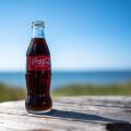 A coca-cola bottle against a sea and blue sky background in summer