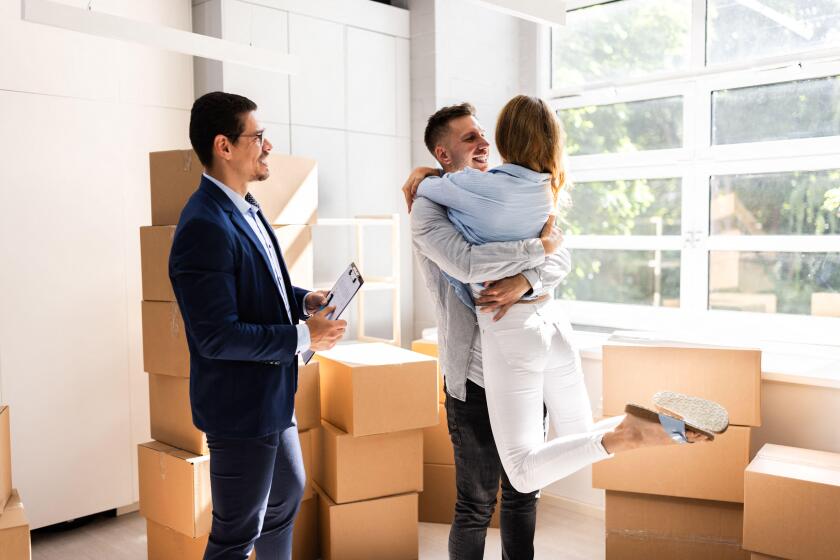 Real Estate Agent And Happy Couple Moving Into New Home