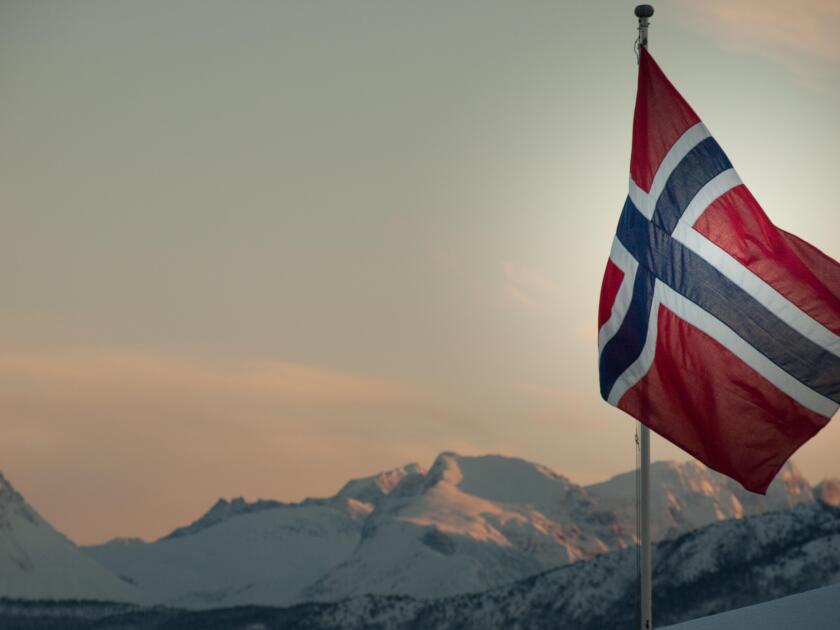 Norwegian flag against snow capped mountains