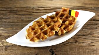Belgian waffles served on a ceramic plate on rustic wooden background