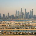 Aerial view of the luxury villas of the Palm Island and of the skyline of Dubai Marina, UAE. Hazy sky, pollution from the city. Futuristic skyline