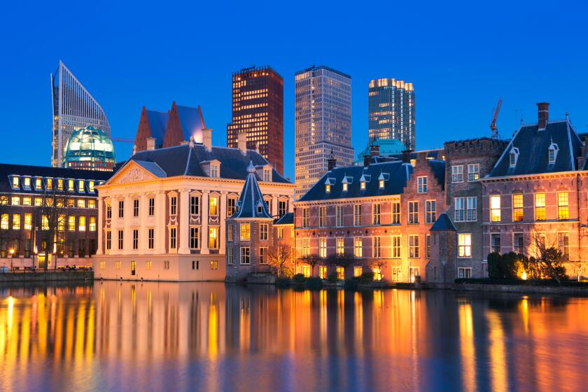 The Dutch Parliament buildings at the Binnenhof from across the Hofvijver pond in The Hague, The Netherlands at night.