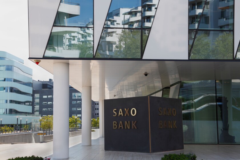 The Saxo Bank building at Tuborg Harbour, Hellerup in Copenhagen, Denmark. Surrounding buildings reflecting in the glass facade.