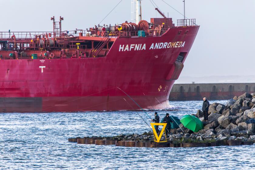 Tanker Hafnia Andromeda, enters the port of Ijmuiden, in North Holland, Netherlands, anglers at the pier,