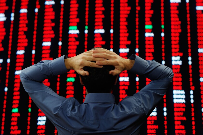 Stock Trader Stood in Front of a Large Display of Stock Prices