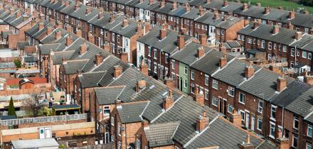 An aerial view above the rooftops of run down back to back terraced houses on a large residential estate in the North of England