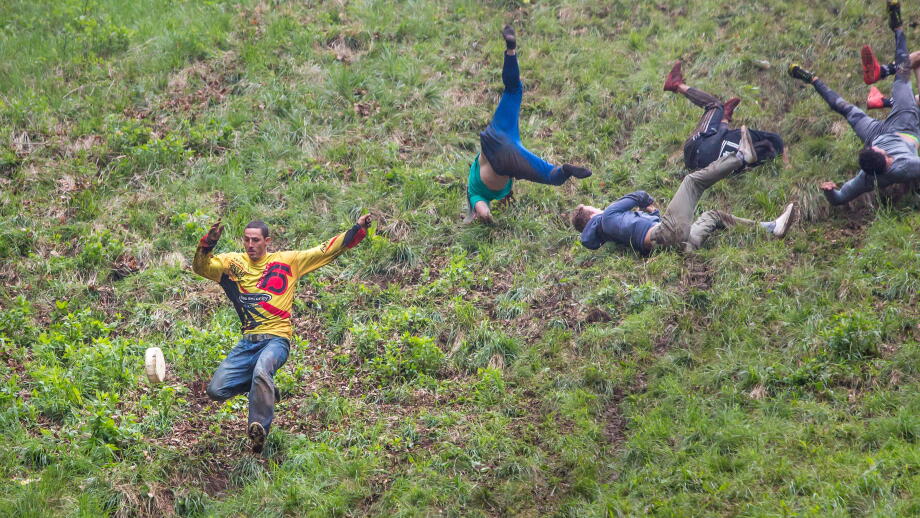 Gloucester, UK. The annual cheese rolling race held at Coopers Hill, Brockworth outside Gloucester. Competitors race down the extremly steep slippery hill chasing a double Gloucester cheese, the winner of each race recieves the cheese as thier prize.