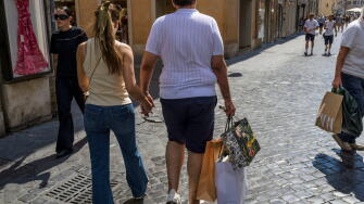 Rome, Italy. July 4, 2026, Rome, Italy: The man of a tourist couple carries three paper bags after purchasing on the day the summer sales begin in Rome. End-of-season summer sales began today in all Italian regions, with the exception of the autonomous pr