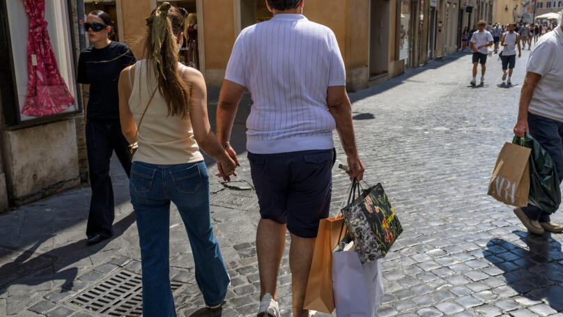 Rome, Italy. July 4, 2026, Rome, Italy: The man of a tourist couple carries three paper bags after purchasing on the day the summer sales begin in Rome. End-of-season summer sales began today in all Italian regions, with the exception of the autonomous pr
