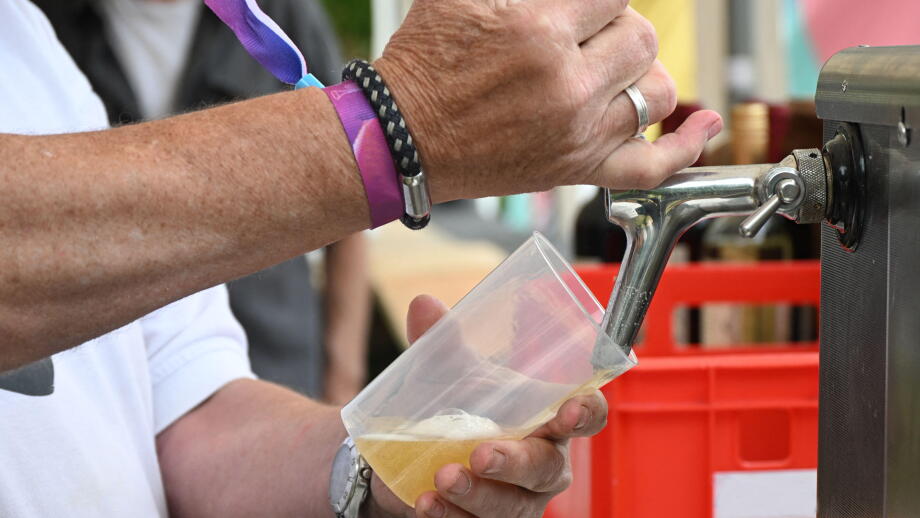 Beer is poured from a tap into a reusable plastic cup at a casual outdoor festival event, concept for sustainable open-air entertainment, fun and cold