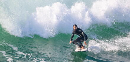 A male surfer riding a wave on a surfboard near Huntington Beach