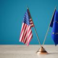 Transatlantic Partnership Concept. USA And European Union Flags Crossed On Golden Stand Against Blue Background. 3d Rendering
