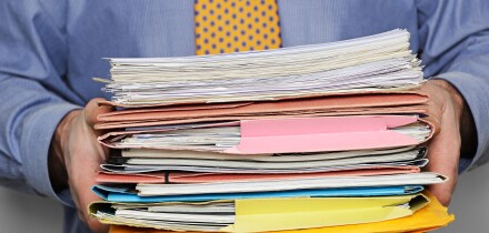 Overworked Businessman Carrying a Stack of Paperwork. Close Up.