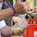 Beer is poured from a tap into a reusable plastic cup at a casual outdoor festival event, concept for sustainable open-air entertainment, fun and cold