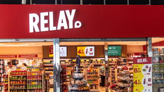 The storefront of a Relay press and convenience store, displaying magazines, snacks and souvenirs, at Barcelona Airport.