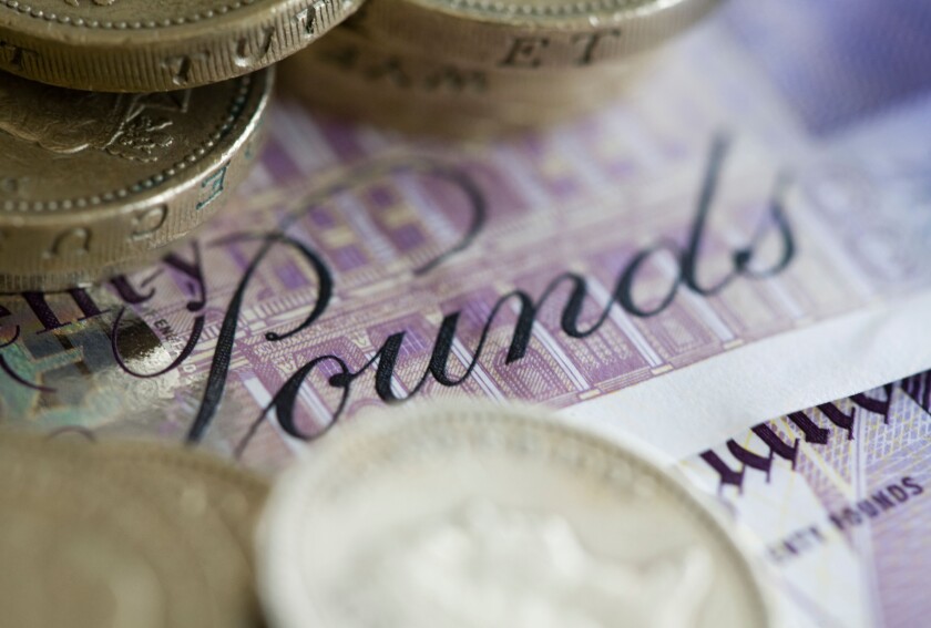 Twenty pound sterling notes and one pound coins are set up for a photograph